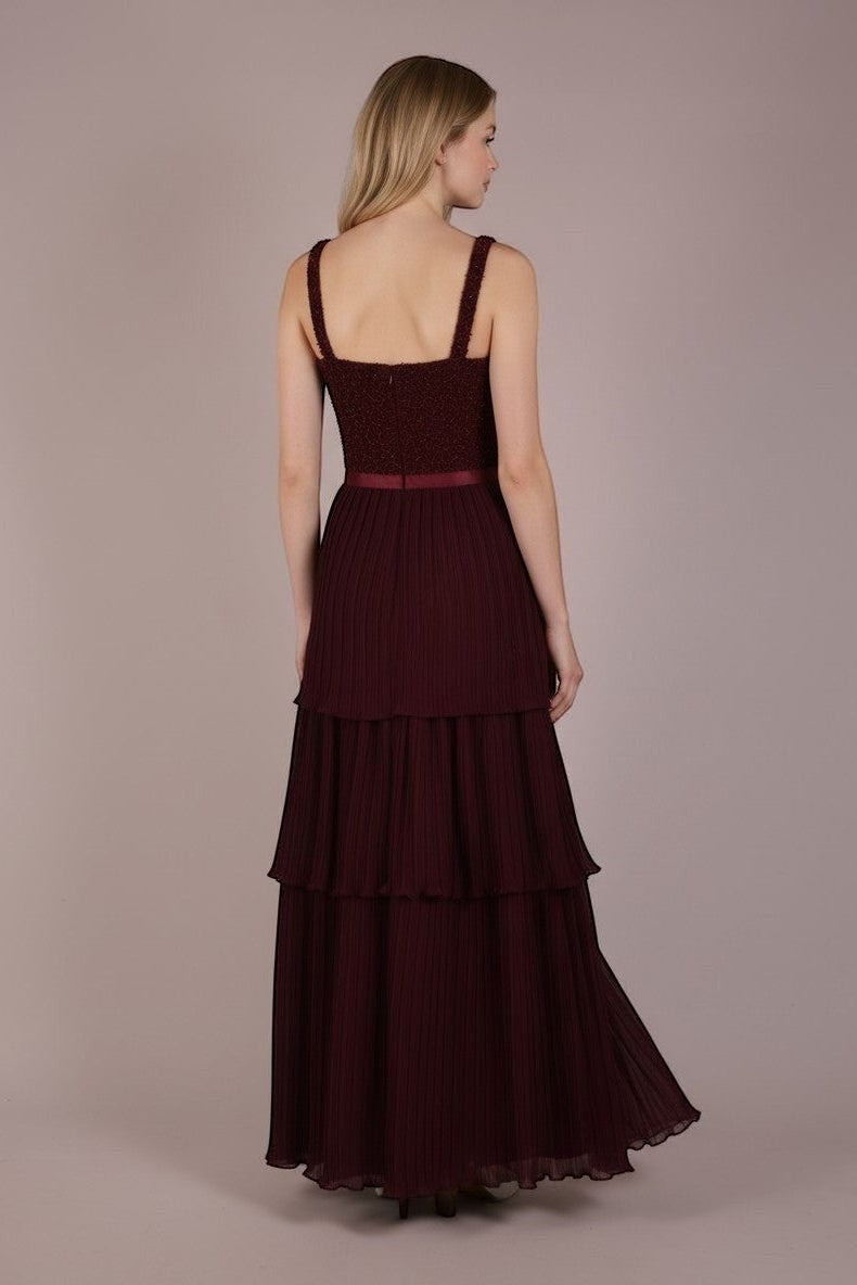 Ageless.ee deep burgundy tiered pleated maxi dress with embellished bodice, velvet waistband, and flowing skirt.